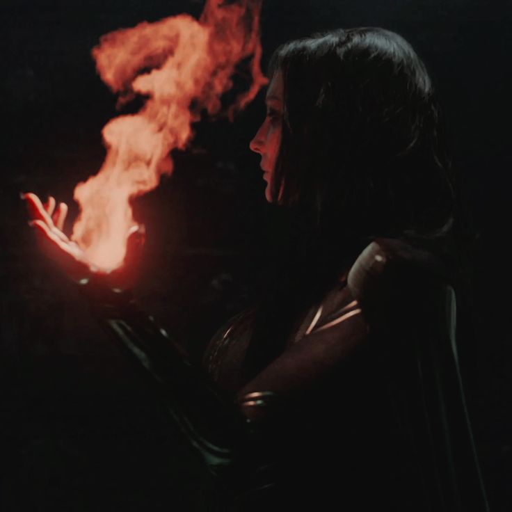 a woman holding a lit object in her hand with flames coming out of the back