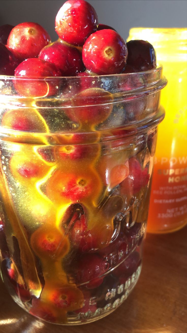 a jar filled with fruit sitting on top of a wooden table