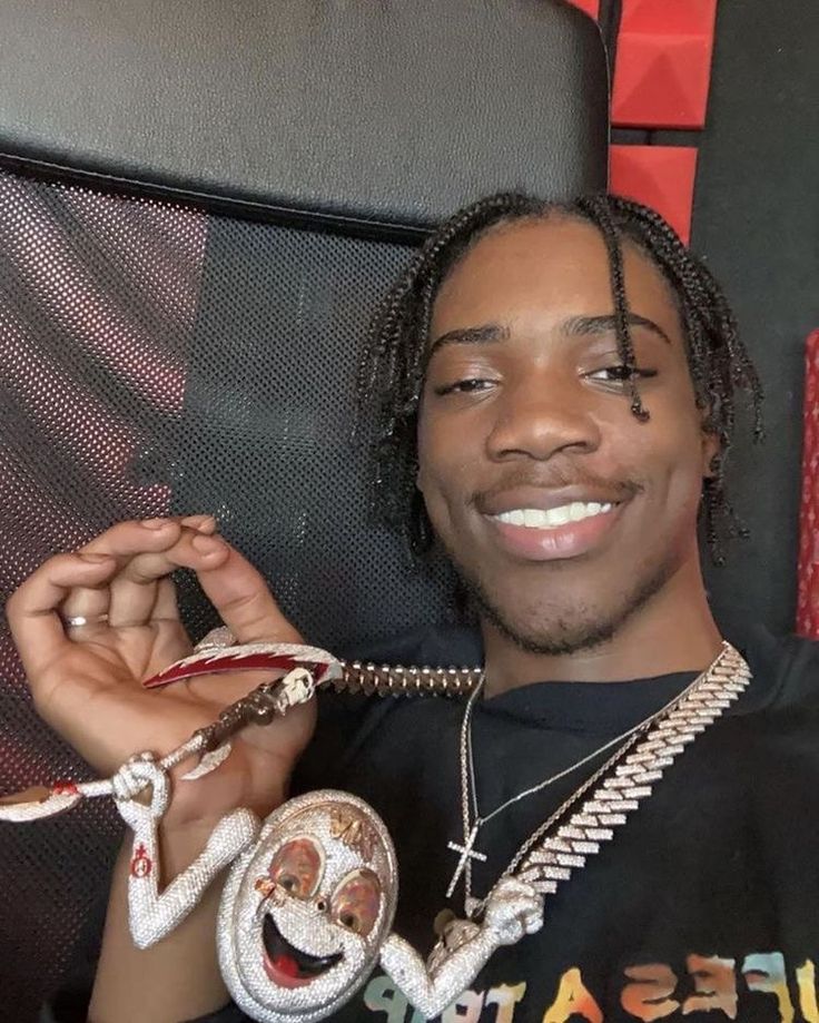 a young man with dreadlocks holding two snakes in his right hand and smiling at the camera