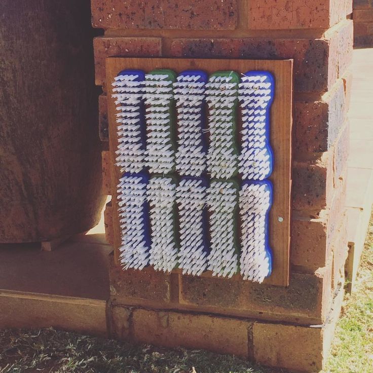 a piece of art made out of crochet sitting on the side of a brick wall