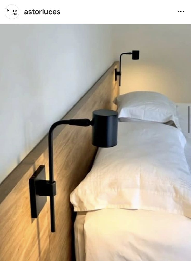 a bed with two lamps on each side of the headboard and one lamp is plugged into the wall