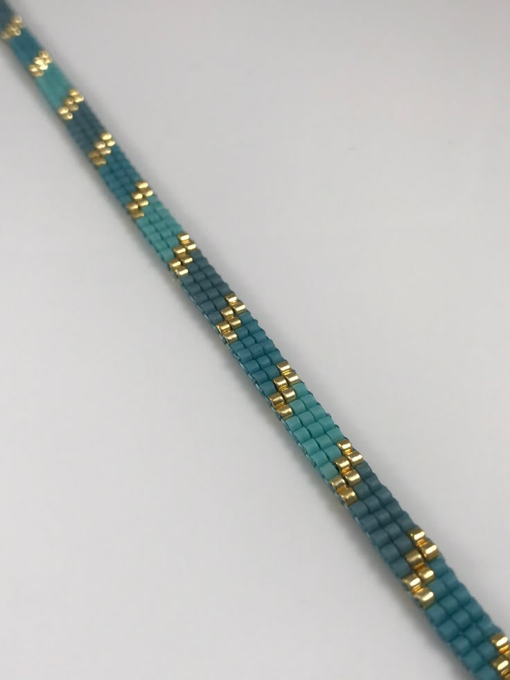 a blue and gold beaded bracelet on a white surface