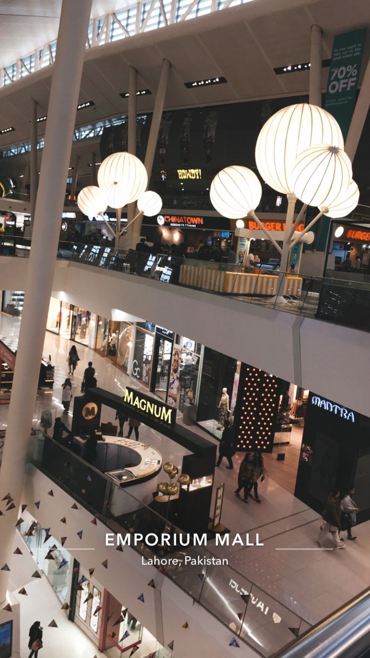 an empty mall filled with lots of people and lights hanging from the ceiling above them