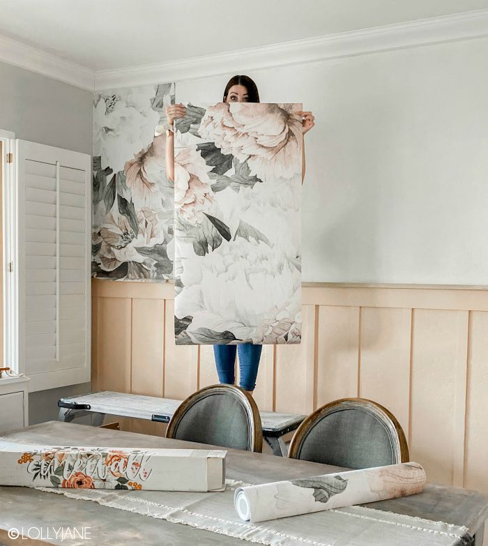 a woman is holding up a large piece of art in the middle of a room