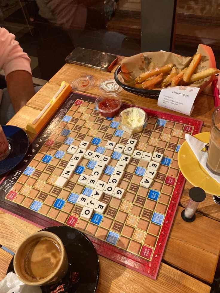 a crossword board game sitting on top of a wooden table next to a cup of coffee