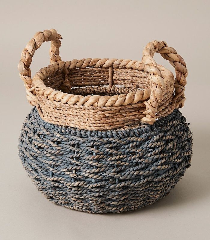 three woven baskets with handles on each side and rope wrapped around the sides, all in different colors