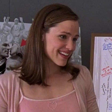 a woman standing in front of a white board with writing on it and smiling at the camera