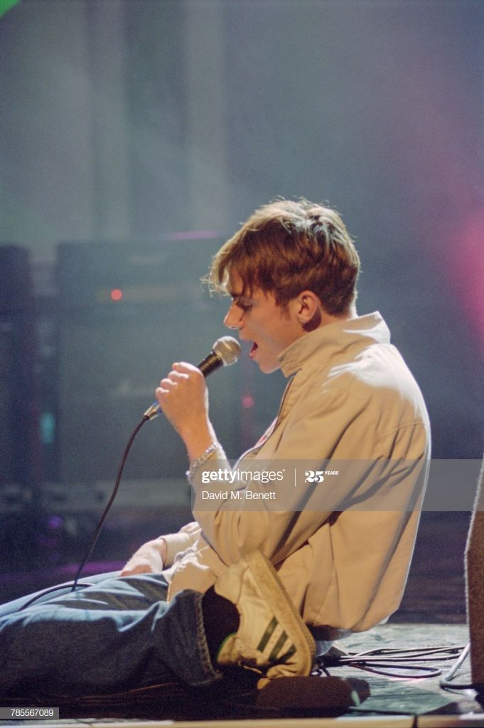 a young man sitting on the floor singing into a microphone