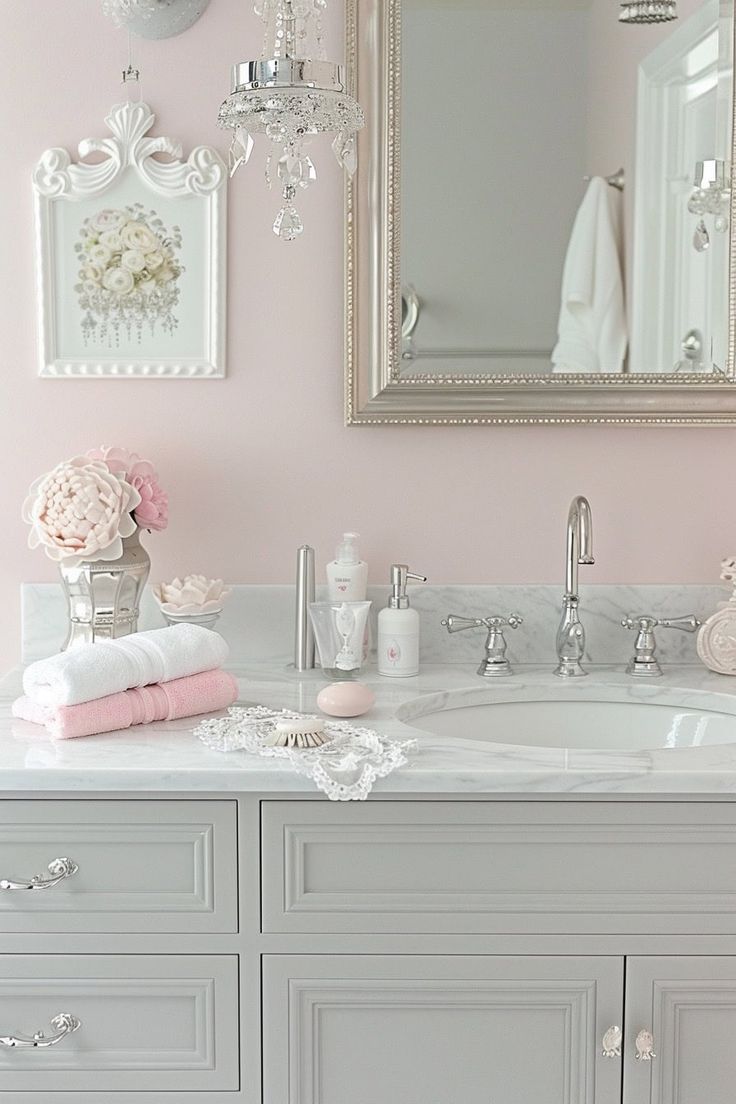 a bathroom with pink walls and white vanity, chandelier and mirror above the sink