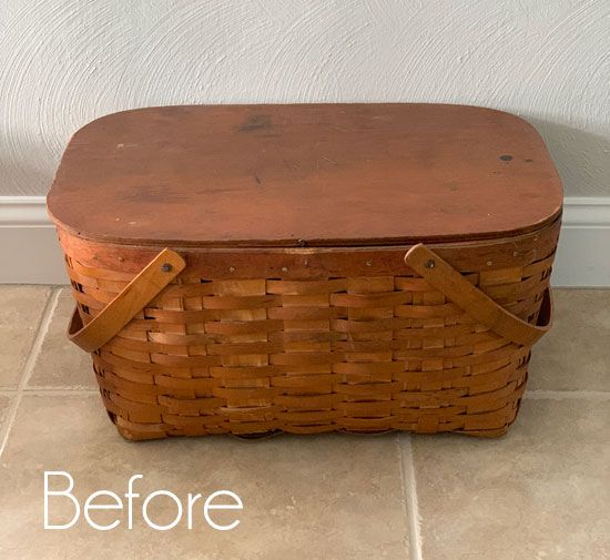 an old wooden basket with leather straps on the bottom is sitting in front of a white wall