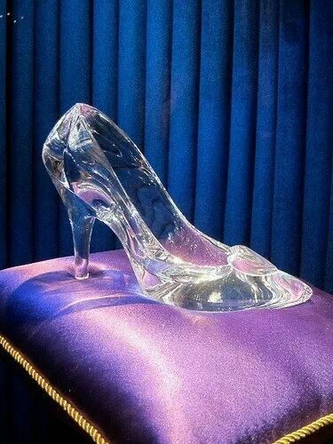 a glass shoe sitting on top of a purple cushion