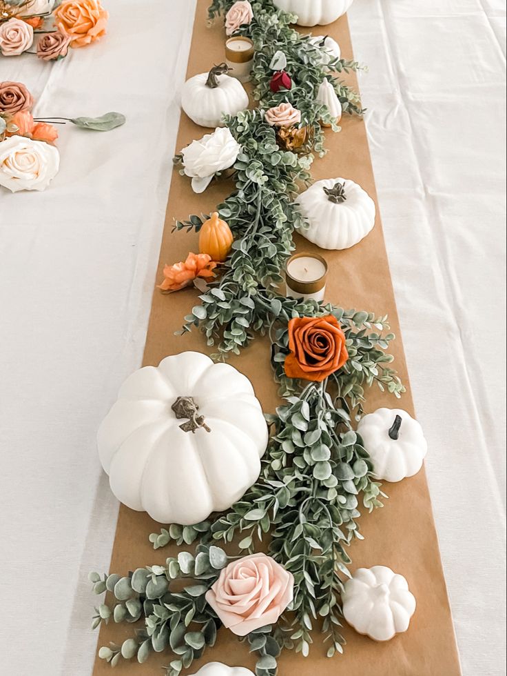 a long table with white pumpkins and greenery