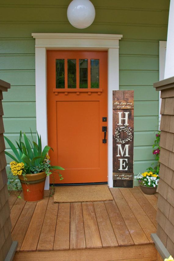 an orange front door on a green house