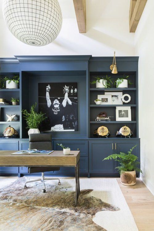 a living room with built in bookshelves and blue paint on the walls, along with an area rug