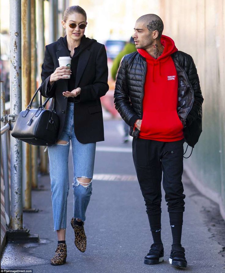 a man and woman are walking down the street with one holding a coffee in his hand