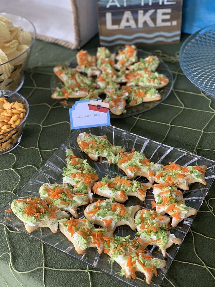 several trays of appetizers on a table with chips and crackers in the background