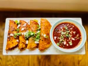 some tacos and salsa on a white plate