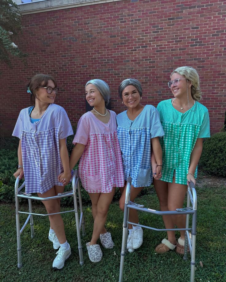 four women standing next to each other in front of a brick building