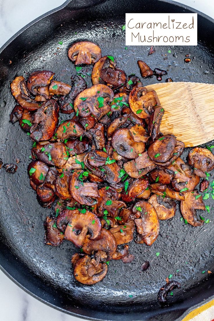 mushrooms are being cooked in a skillet with a wooden spatula on the side