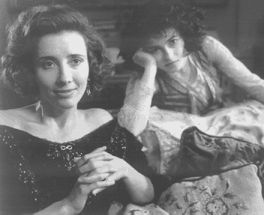 an old black and white photo of two women sitting on a bed, one with her hand near her face