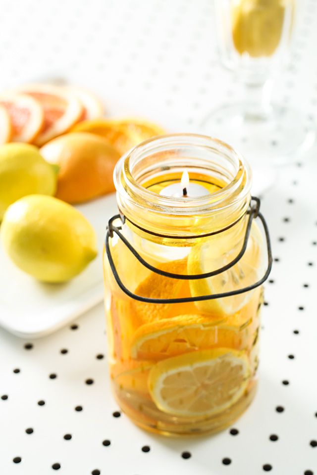 a glass jar filled with lemons and oranges on top of a white table