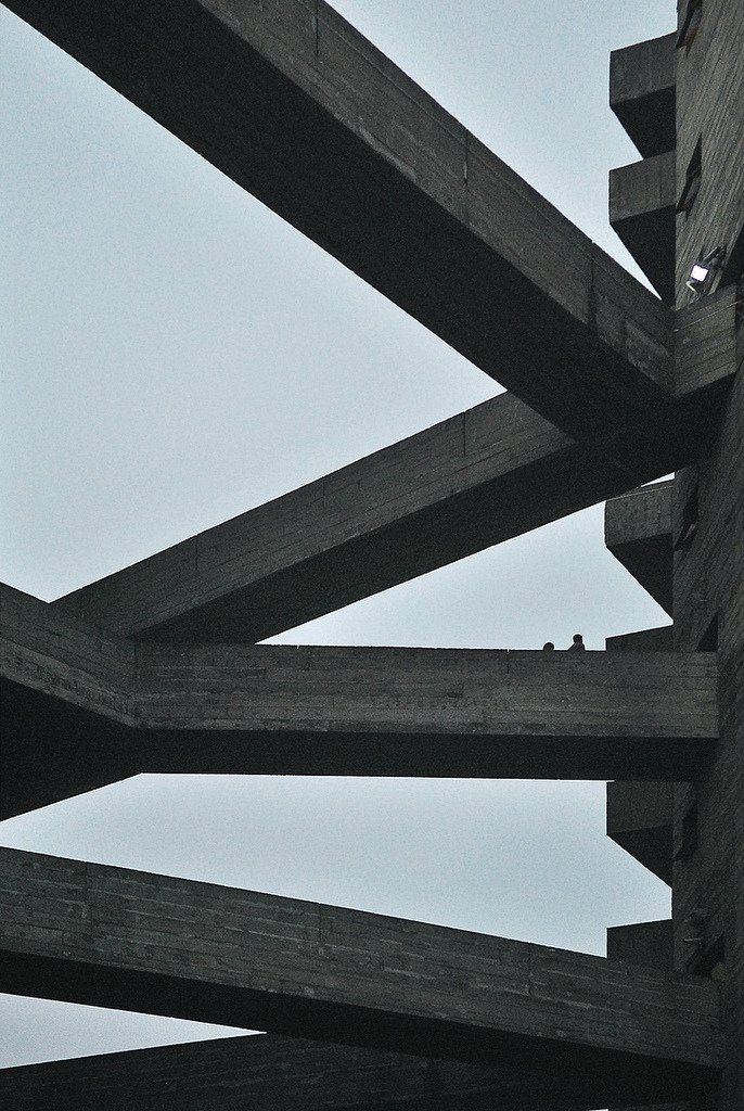 a black and white photo of a building made out of wooden beams with a clock on the top