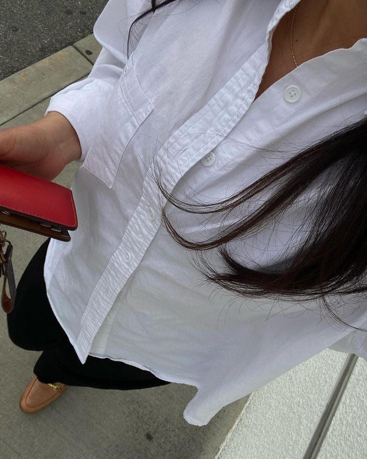 a woman in white shirt holding a red wallet