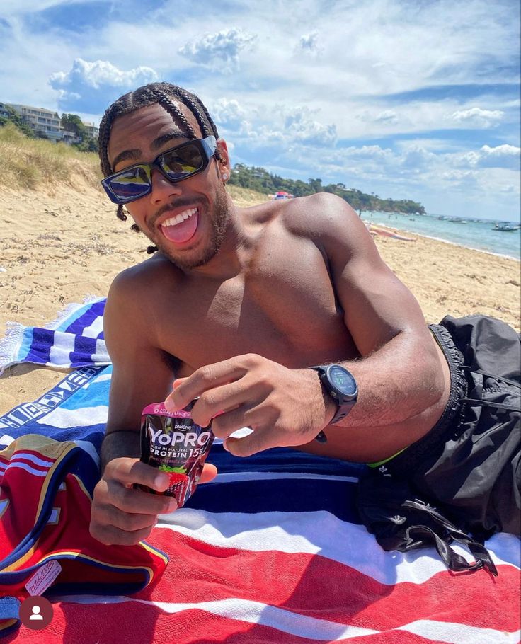 a shirtless man sitting on top of a beach towel