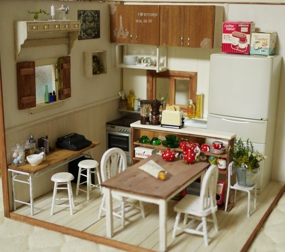 a doll house kitchen and dining area with table, chairs, refrigerator and stove top oven