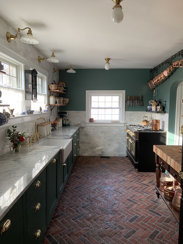 a kitchen with green cabinets and brick flooring, along with white counter tops on both sides