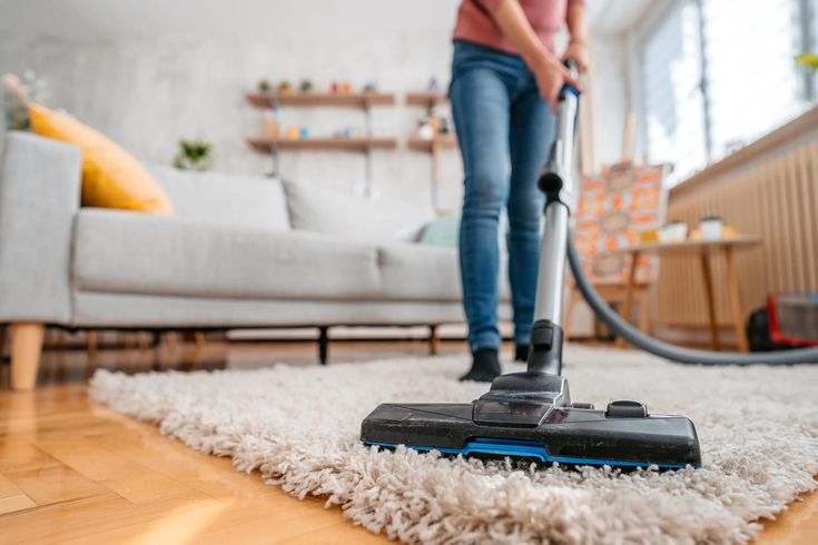 a woman is vacuuming the floor in her living room with a rug on the floor