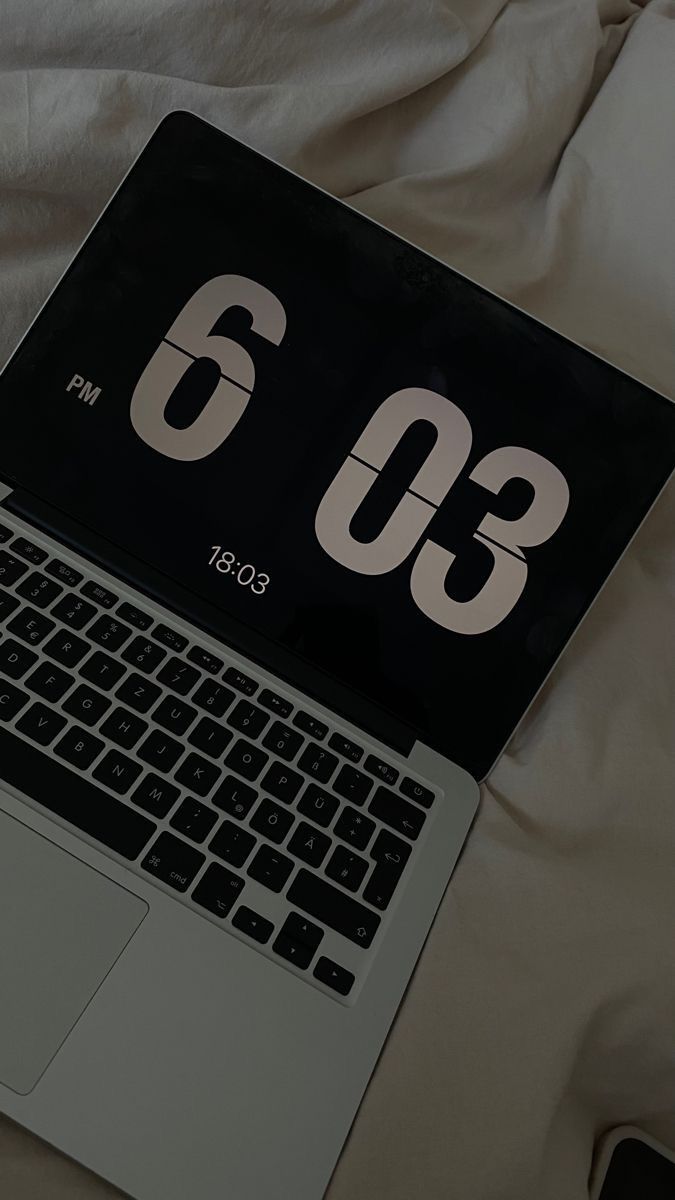 an open laptop computer sitting on top of a bed next to a white mouse and keyboard