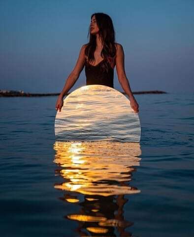 a woman standing in the water holding a surfboard