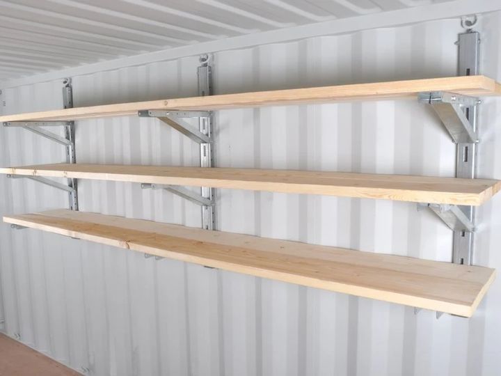 three wooden shelves in a storage room with metal brackets on the bottom and one shelf above them