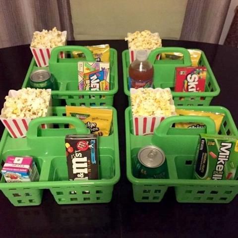 four green baskets filled with snacks and drinks on top of a black table next to a window