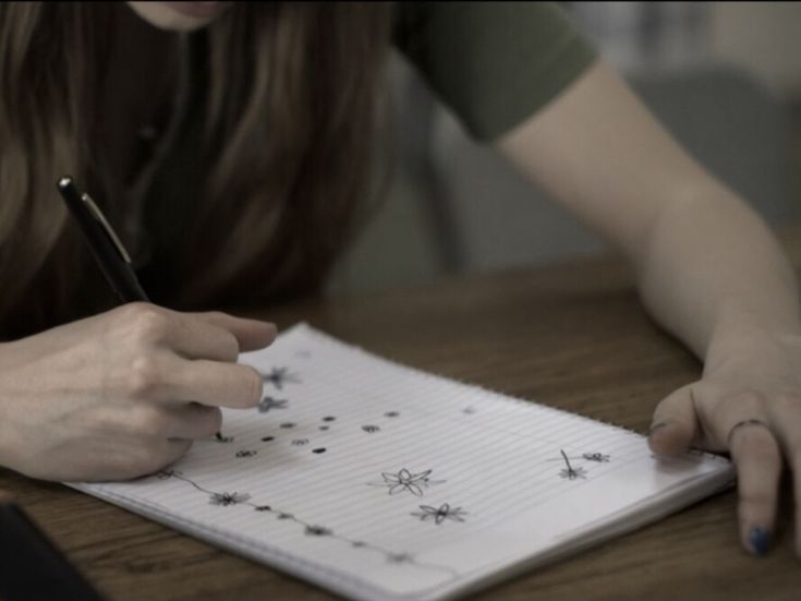 a woman writing on a notebook with stars drawn on it