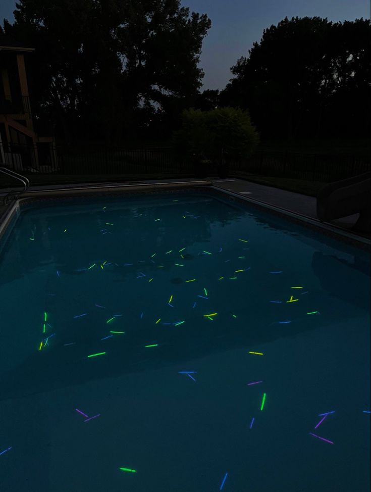 a swimming pool with glow sticks in the water