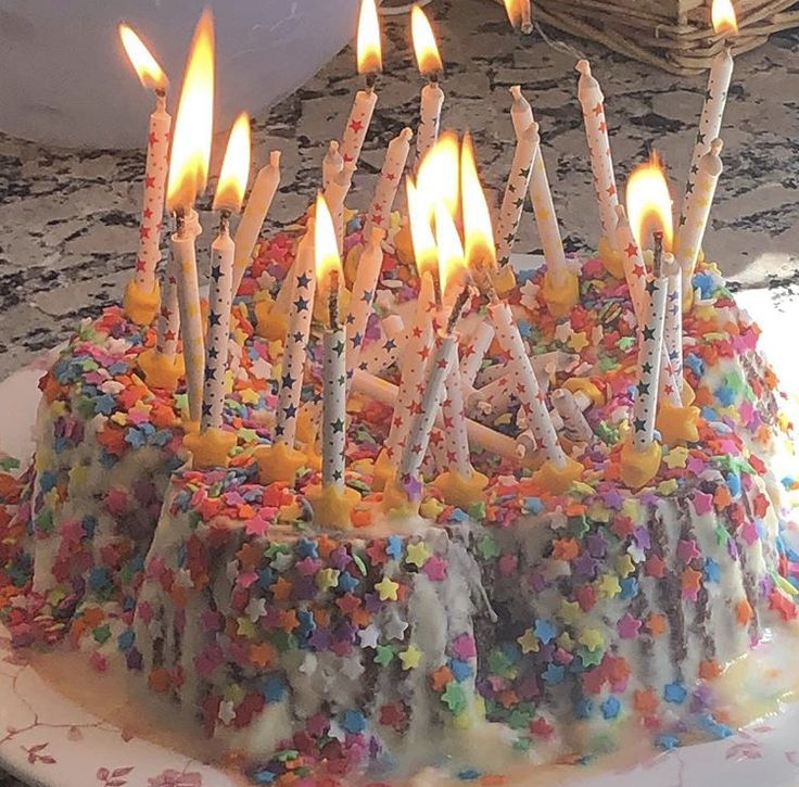 a birthday cake with many lit candles on it and sprinkles all over the top