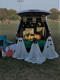 the back end of a van decorated for halloween with ghost decorations and pumpkins on it