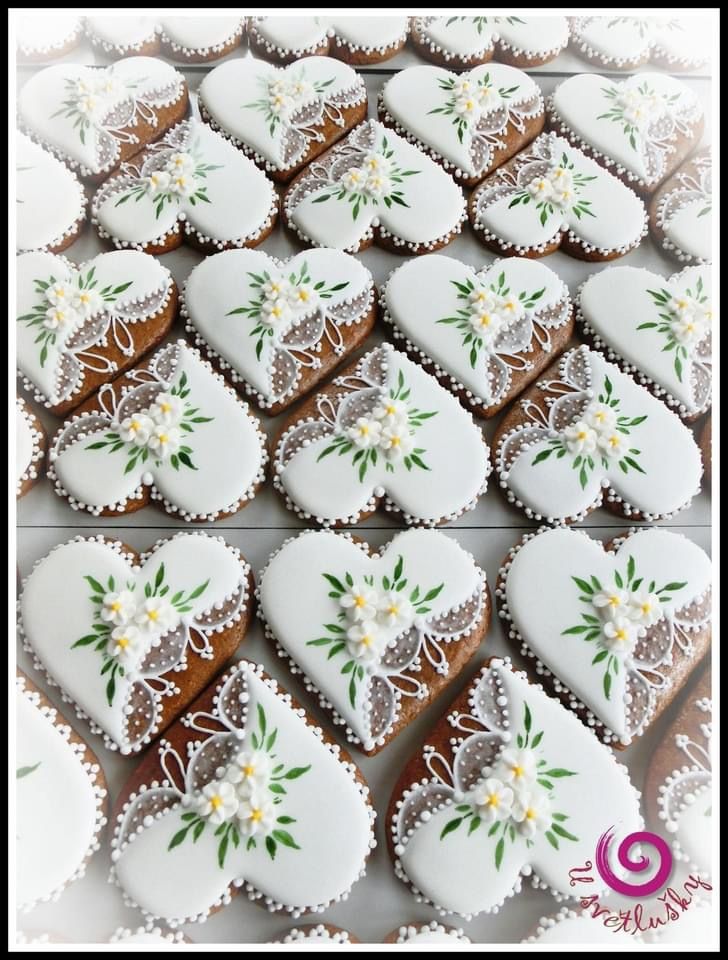 several decorated heart shaped cookies with flowers and leaves on them, all in white frosting