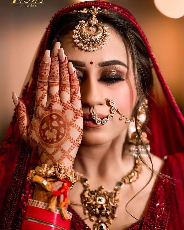 a woman with henna on her face and hands, covering her eyes from the sun