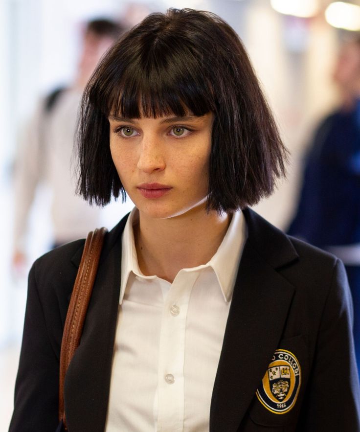 a woman with short black hair wearing a police badge on her blazer and white shirt