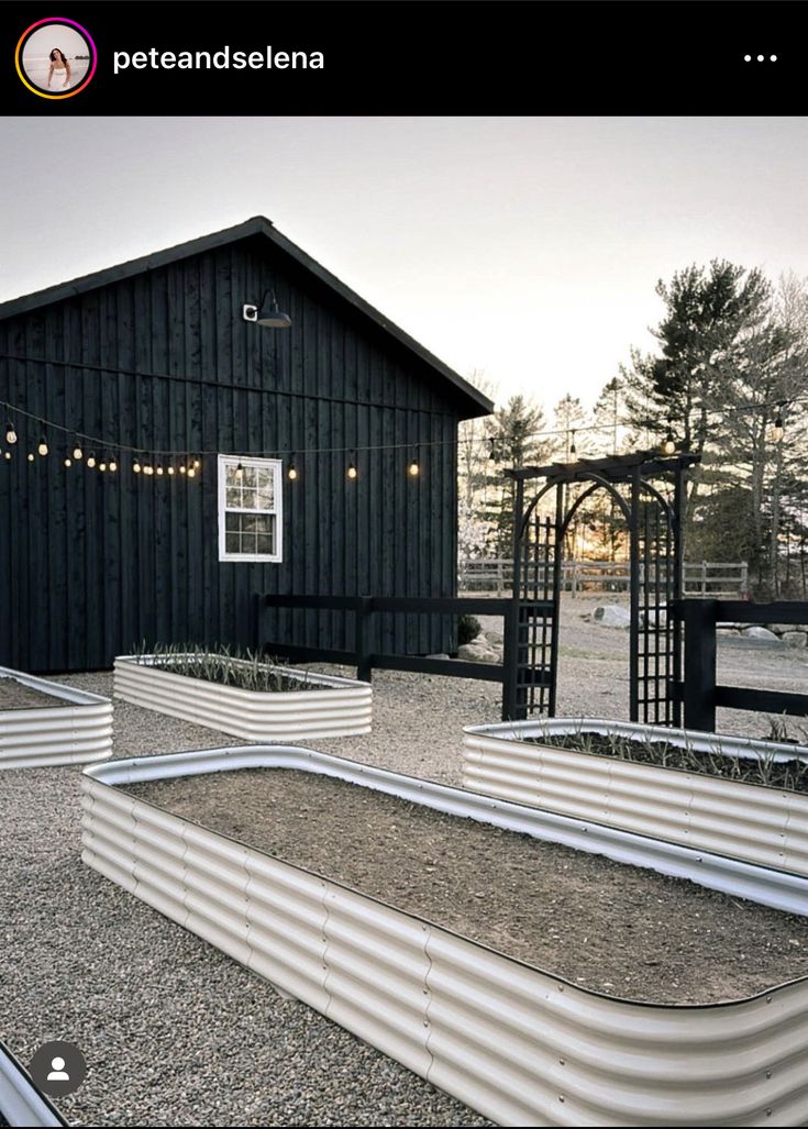 there are several raised beds in front of the building with string lights strung around them