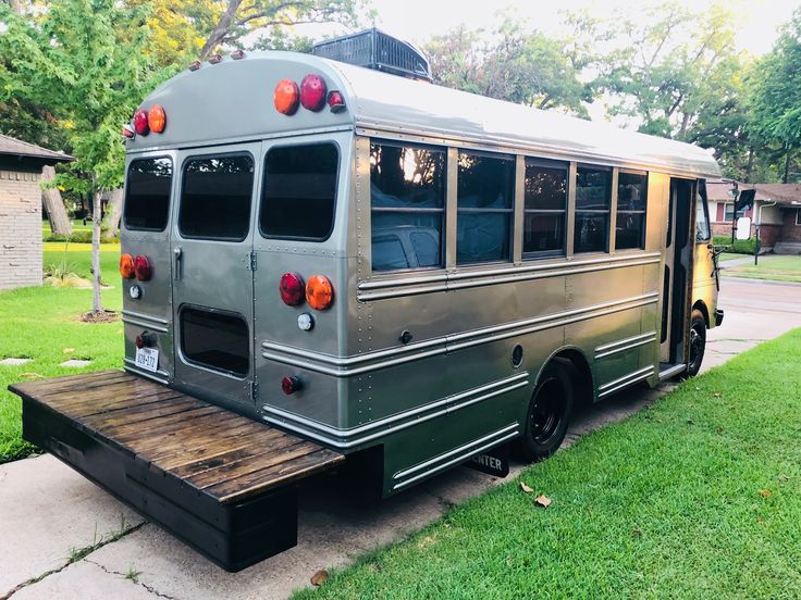 an old school bus is parked on the side of the road in front of a house