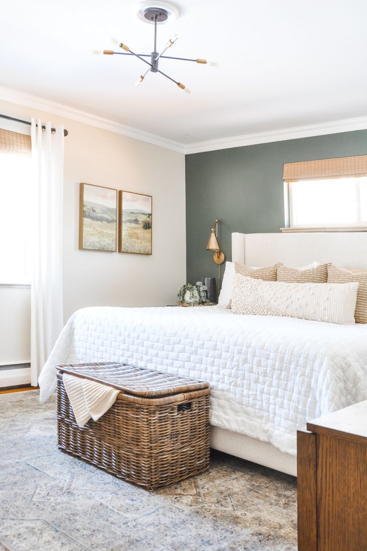 a bedroom with a large bed and white linens on the pillows, along with a wicker basket