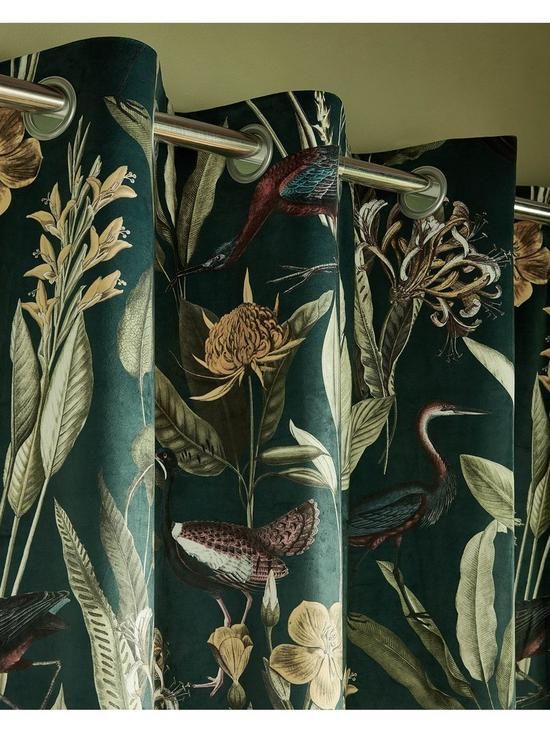 the curtains are decorated with tropical flowers and birds on green velvet fabric, hanging from a metal rod