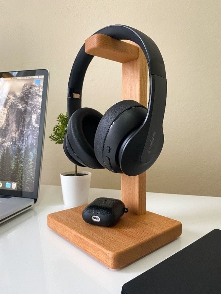 a laptop and headphones are on a desk next to a wooden stand with a mouse