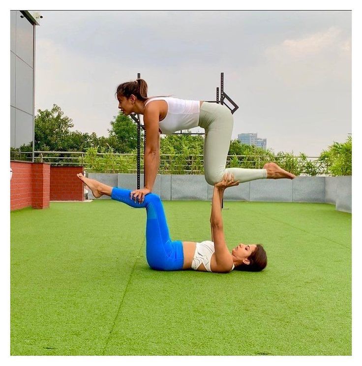 two women are doing yoga on the grass