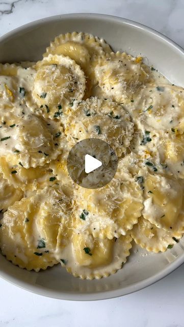 a white bowl filled with ravioli and cheese on top of a marble countertop