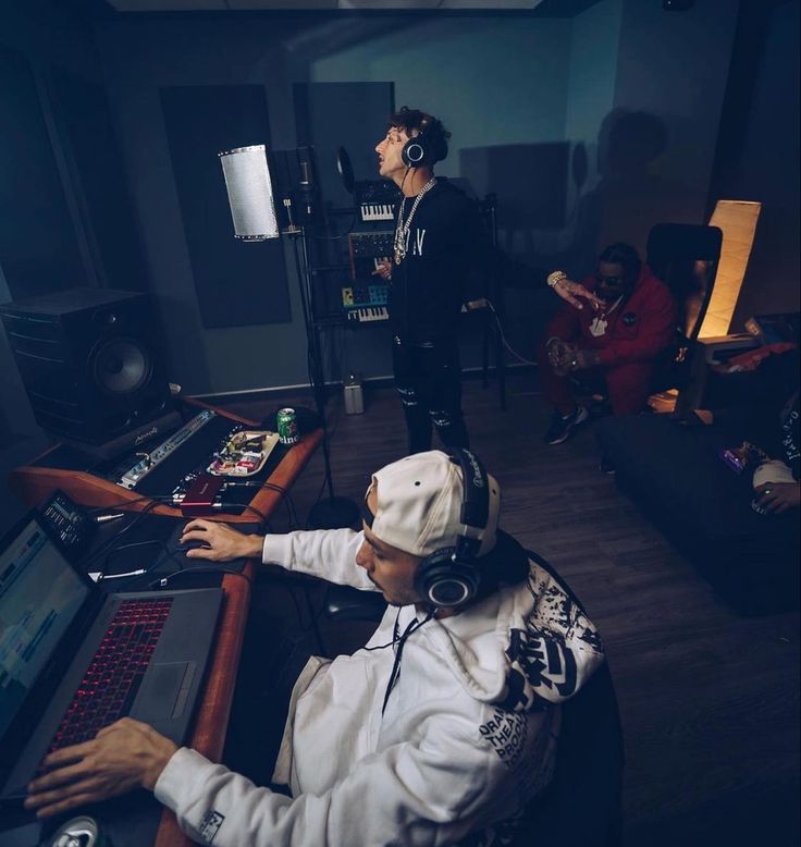 a man wearing headphones sitting in front of a laptop computer next to another person